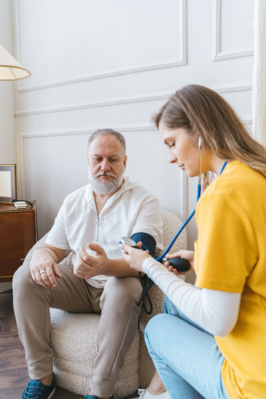 A nurse checking an older man’s blood pressure at home