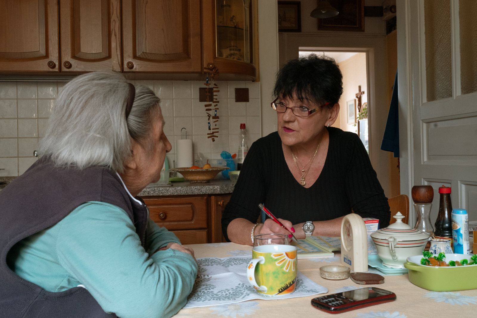 A carer chatting with an older woman at her kitchen table