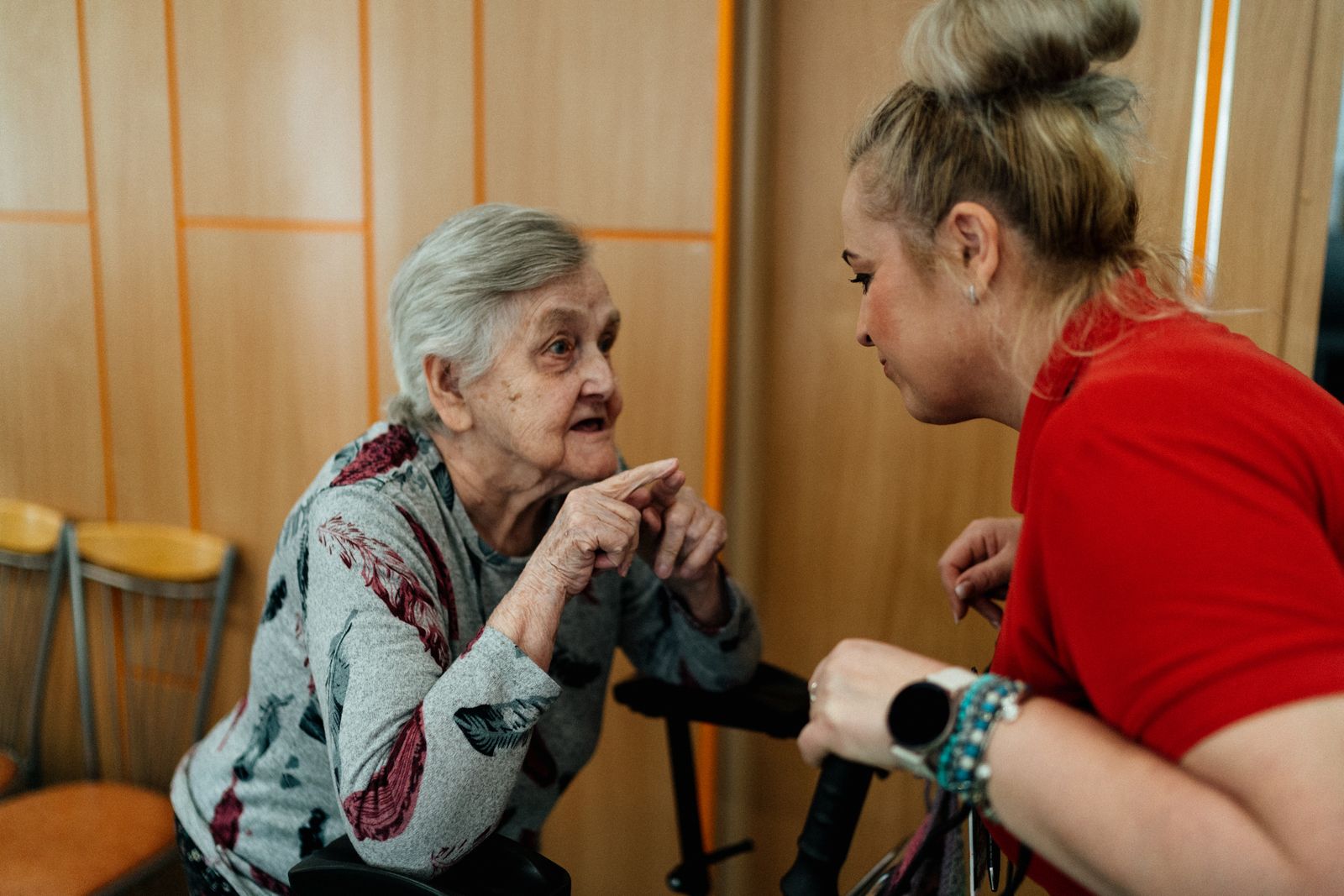 A care worker kneeling to talk with a resident at eye level