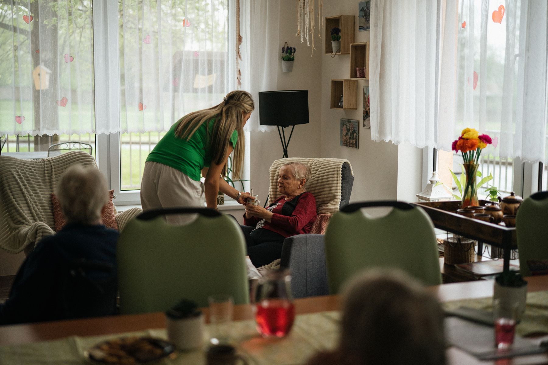A care worker helping a resident in a bright care home lounge